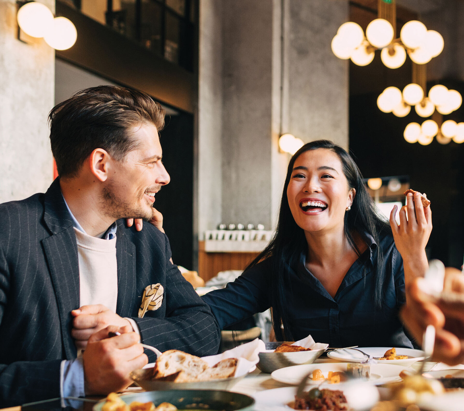 A well-dressed couple dining at an upscale, elegantly lit restaurant